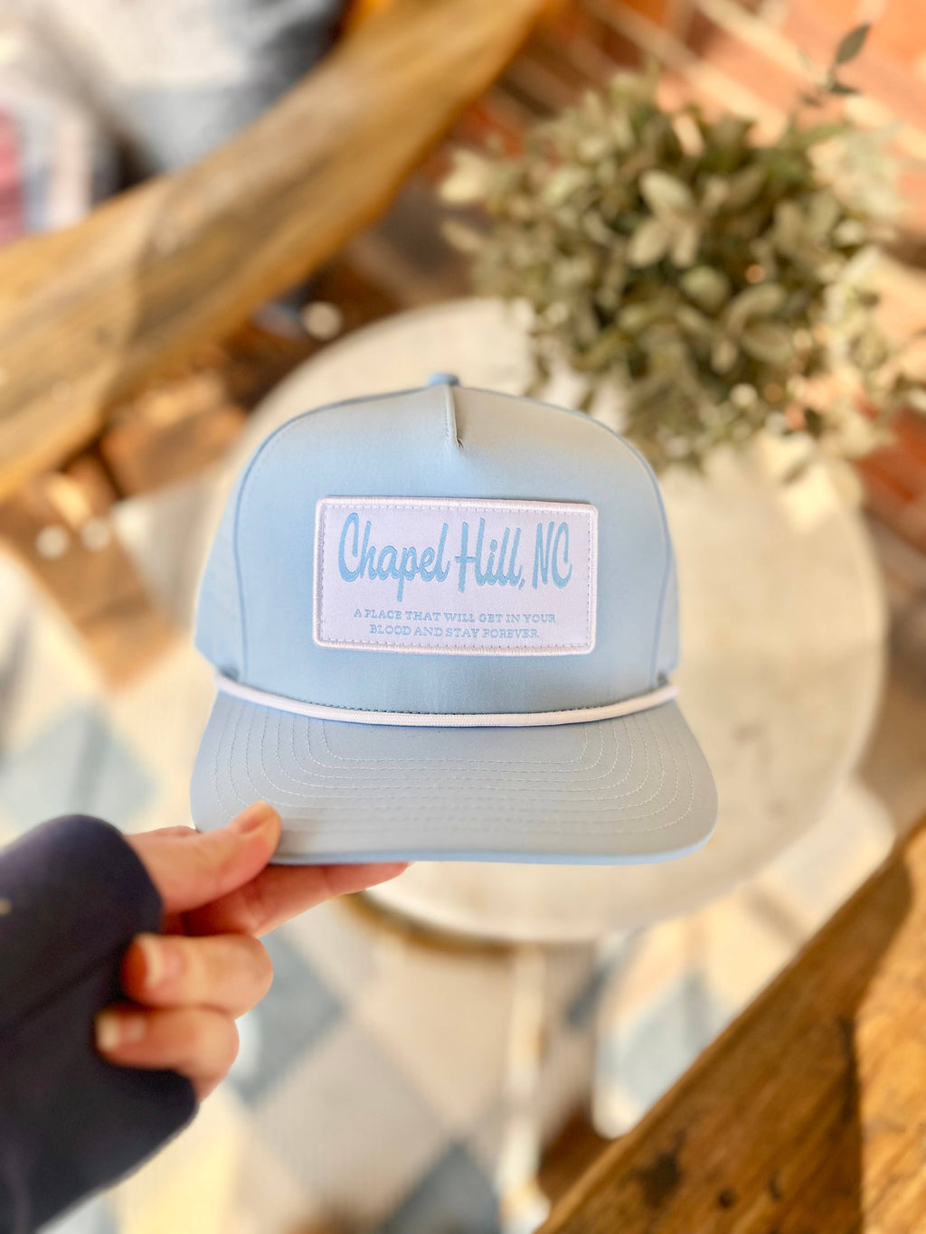 UNC Next Chapter gift box lifestyle flat lay with Tar Heel themed accessories and blue ribbon