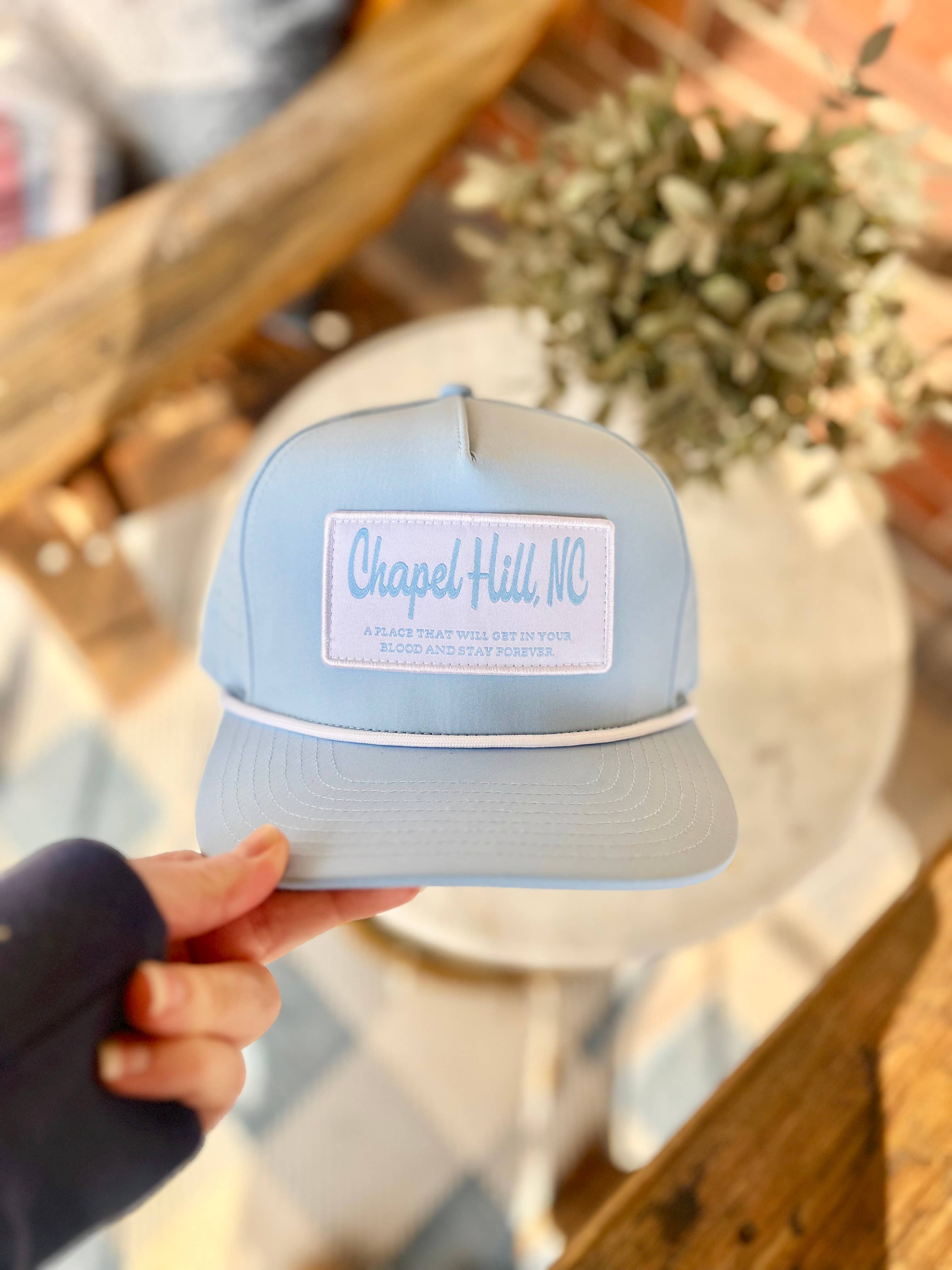 UNC Next Chapter gift box lifestyle flat lay with Tar Heel themed accessories and blue ribbon